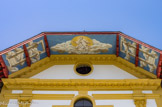 <center>Saint-Nicolas-de-Véroce</center>Le décor de l’auvent, création du peintre Gabriel, trouve sa place entre les pièces de charpente de couleur sang de bœuf comme le portail de la façade. Le décor a été peint sur des toiles marouflées. De chaque côté, des fenêtres ouvrent sur le ciel, dans la pure tradition baroque. Le panneau central oublie la Trinité pour représenter Dieu le père avec la Colombe de l’Esprit Saint dans un ciel ouvrant sur la lumière. On retrouve là le «trompe-l’œil» caractéristique du baroque.