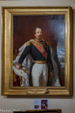 <center>Conflans : Musée d’Art et d’Histoire.</center> Portrait de Napoléon III.
Huile sur toile - Seconde moitié du XIXe siècle d’après l’œuvre de Franz Xavier WINTERHALTER (1805-1873).
Le 12 juin 1860 la Savoie est officiellement rattachée à la France.
Désormais les Savoyards ont un empereur : Napoléon III Albertville devient sous-préfecture et un bâtiment est aménagé à cet effet. Les nouveaux locaux accueilleront les portraits officiels de l’Empereur et de l’Impératrice Eugénie. Seul le tableau de l’Empereur est parvenu jusqu’à nous.
On découvre Napoléon III représenté en pied devant le palais des Tuileries. Vêtu d’un uniforme sobre, il porte le collier de la Légion d’Honneur et l’écharpe rouge de cet ordre barre sa poitrine. Sur ses épaules, le manteau du sacre doublé d’hermine.