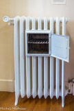 <center>Conflans : Musée d’Art et d’Histoire.</center> Radiateur chauffe-plat. Fonte.
Le chauffage central fait son apparition dans les intérieurs français vers les années 1880 et se généralise après 1930. Grâce à l'emploi de la fonte et à leur contenance importante, les radiateurs en fonte possèdent une forte inertie thermique : ils refroidissent très lentement après la coupure du système de chauffage. Ces propriétés expliquent qu'ils sont parfois utilisés comme chauffe-plat.