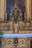 <center>Conflans et son Église baroque Saint-Grat.</center> Le tabernacle, auquel manquent, à droite et à gauche, deux statues, (l’une de Saint Pierre, l’autre de Saint Paul), volées le 27 août 1959. Ce tabernacle porte une exposition, dont le couronnement est tenu par deux anges, qui remuent bras et jambes. Puis, par horreur du vide, le sculpteur a couvert les espaces nus de bouquets, rinceaux, vases, guirlandes, qui font du retable une véritable ciselure. sur la porte, l'Agnus Dei (agneau de Dieu).
