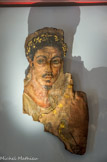 <center>Le Musée d'Art Sacré du Gard. </center> Portrait d'homme, dit portrait du Fayoum. Ce romain aisé établi en Egypte sur les bords du Nil vivait sous les empereurs Trajan et Hadrien (Vers 110-130 de notre ère) ainsi qu'en témoignent la moustache, la barbichette et la découpe de la chevelure, typiques de la dernière mode de Rome.
Ce portrait était placé au niveau du visage de la momie et servait d'identification, alors que le linceul encore en partie conservé montre les rites propres à l'Egypte des pharaons. Le faucon coiffé du disque solaire fait en effet référence au dieu Ptah-Sokar-Osiris. C'est l'une des plus anciennes peintures sur chevalet que l'on connaisse au monde. Il n'en existe que 800 environ.
