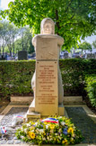 <center>Le cimetière du Père Lachaise </center> Stèle de Neuengamme. Sculpté par Pierre Honoré, grand prix de Rome, dans de la pierre de Vilhonneur, le monument de Neuengamme représente une figure de femme accroupie, les bras posés sur un bloc gravé. Le regard perdu au loin, elle symbolise le maintien de l’espoir et l’humanité ayant vaincu la force brute. Le style rappelle celui de certains monuments de la Grande Guerre, mais la silhouette féminine montre les traces de l’amaigrissement et de l’épuisement des déportés. Sur l’avant du bloc, sont sculptées trois silhouettes en à-plat appuyées les unes contre les autres. Elles témoignent de la fragilité de la condition des déportés, mais elles soulignent également l’importance de la solidarité pour maintenir la survie. Au pied du monument, est posée une pierre sculptée en hommage aux victimes du Cap Arcona.
Le KL Neuengamme ouvre en juin 1940, près de Hambourg. Neuengamme est le principal camp d’Allemagne du Nord. Près de 106 000 détenus sont immatriculés à Neuengamme et dans ses 80 Kommandos. 55 000 environ y périssent.