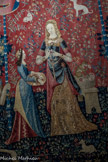 <center>Tapisseries de la Dame à la licorne  </center> L'odorat : pendant que la dame fabrique une couronne de fleurs, à l'arrière plan, un singe respire le parfum d'une fleur dont il s'est emparée ;