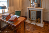 <center>Arrière-cabinet.</center>Petit écran de cheminée néoclassique. De forme rectangulaire reposant sur deux pieds en bois sculpté et doré, à décor de rosaces reliées par des attaches. Sur la traverse inférieure, bordure de feuilles d'eau, la partie supérieure ornée de godrons. La feuille est garnie d'un damas de soie bleu-vert.