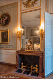 <center>Chambre de Monsieur Thierry de Ville-d'Avray</center>Paire de chenets en bronze doré constitués d'un socle quadripode dont le fût est orné de guirlandes de fruits, surmonté d'un pot à feu ovoïde à deux têtes de bélier et qui est lié par une frise de godrons à un plus petit socle, orné de guirlandes de feuilles de laurier, et surmonté d'un brûle-parfum. <br> Pendule à portique en marbre blanc rehaussé d'ornements en bronze doré et patiné. Elle se compose de deux piliers à base en volute, ornés de figures féminines en termes coiffées d’un némès et flanquées de rinceaux. Ils sont surmontés de deux sphinges tournant le dos au cadran dont le culot ajouré de branchages est surmonté d’un aigle aux ailes déployées. Le socle, agrémenté de trois reliefs figurant des bacchanales de putti, repose sur des pieds en laiton. 1750-1799.<br> Tableau : Sainte Famille, en forme de tondo représentant la Vierge, l'enfant Jésus, Sainte Élisabeth et le petit saint Jean-Baptiste. Dans un cadre très resserré apparaissent la Vierge traditionnellement représentée de trois-quarts, contemplant l’enfant Jésus – le corps tourné vers la gauche et regardant par-dessus son épaule, vers le spectateur – qu’elle porte sur ses genoux. A ses côtés se tient sainte Élisabeth avec son enfant souriant, saint Jean-Baptiste, qui déjà pointe son doigt en direction du Christ pour signifier 