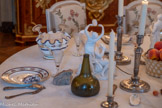 <center>La Salle à manger </center>Paire de flambeaux.  Antoine Boullier. 1779-1780. argent. Le pied circulaire présente un quart de rond ciselé orné d'un décor de feuilles d'acanthe. La tige se compose d'un fût cannelé de section circulaire, se rétrécissant vers la base, semblant jaillir d'une collerette de feuilles d'acanthe et entouré dans sa partie haute d'une cordelette. Au-dessus d’une bague unie, l'épaulement présente un quart de rond sur lequel alternent des feuilles lancéolées et des godrons. Quant au binet, en forme de vase, il est orné dans sa partie inférieure de feuilles lancéolées sur fond amati et porte, en sa partie supérieure, un collier de perles. Le binet est accompagné d'un manchon intérieur amovible (postérieur ?) dans lequel vient s'engager la bobèche : la collerette de cette dernière porte une cannelure brettée. <br> Surtout : Le Tambourin. Groupe en biscuit représentant une bacchante debout, les bras levés, jouant du tambourin, un panier de fruits renversé contient des fruits à ses pieds. A droite, un satyre nu est assis, la tête penchée vers le ciel, et joue de la flûte.