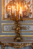 <center>Salon des Amiraux.</center>Paire de candélabres en bronze ciselé et doré représentant un putto tenant une corne d'abondance de laquelle s'échappent huit bras de lumière. Il prend place sur une base de rochers soutenue par quatre pieds en rinceaux feuillagés. Le putto, en contrapposto, porte une cape nouée autour de son cou et regarde vers le bas tout en maintenant d'une main la base végétale de la corne d'abondance et levant l'autre bras à hauteur des fruits qui en sortent. Les bras de lumière prennent la forme de branches feuillues tortueuses, se terminant par un bouton de rose. Ces créations du Second Empire s'inspirent des formes du style Louis XV. 1850-1874.
