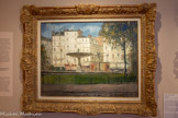 <center>Musée de Montmartre</center>MAURICE UTRILLO (1883-1955)
Place Pigalle, 1910
Huile sur bois
Musée de Montmartre, collection Le Vieux Montmartre, inv. 2008.1.1. <br>
Maurice Utrillo, fils de Suzanne Valadon et de père inconnu, est reconnu en 1891 par Miquel Utrillo (1862-1934), peintre, critique d’art et ingénieur espagnol. Autodidacte, il pratique la peinture sans aucun académisme. Il représente Montmartre, un monde sans visage, à travers des paysages urbains vides, souvent composés à partir de cartes postales, comme l’illustre Place Pigalle. Le blanc des immeubles, le bleu du ciel et la fontaine font de la place un lieu paisible. La touche domine la toile comme chez les impressionnistes ou encore Pissarro qu’Utrillo admirait tant.
Place Pigalle fait partie de la période blanche d’Utrillo, durant laquelle il mêle à ses couleurs du plâtre obtenu â partir du gypse des carrières de Montmartre. Celle-ci, la plus célèbre de son œuvre, se caractérise par des tons blancs et un espace vidé de toute présence, ne laissant aucun soupçon relatif aux tourments du jeune peintre qui souffrait d’alcoolisme.