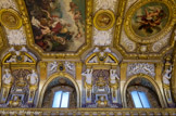 <center>LA SALLE DES CONFERENCES </center> Des lunettes, flanquées de pilastres et de cariatides terminées en gaîne, pénètrent les côtés des deux portions de la voûte. Ces cariatides soutiennent un entablement, couronné d’un fronton coupé. L'Âge de la Paix et le médaillon La Chevalerie.