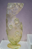 <center>Vase aux médaillons </center> Il est décoré de losanges au centre desquels se trouvent des médaillons ornés d'un visage de profil, peut-être celui d'Apollon ou d'un athlète. Ce type de trophée était remis à l'aurige vainqueur d'une course de chars pour une libation en l'honneur des dieux. Verre soufflé
Seconde moitié du IIe - début du IIIe s.