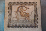 <center>Mosaïque</center> Cette mosaïque est probablement associée à un culte solaire,. Dans toutes ces religions, qui ont d’ailleurs partiellement imprégné les croyances chrétiennes, les astres sont emportés dans le ciel par un quadrupède (en général un cheval) ou un char. Ici, l’animal est un taureau. Ce qui ferait penser au culte de Mithra. Le voile qui flotte au dessus de la déesse pourrait représenter le Ciel.