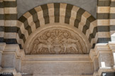 <center>La Basilique Cathédrale Sainte-Marie-Majeure</center>Au-dessus de la porte de droite, le symbole de la Résurrection, deux griffons gardiens de l’arbre de vie, par Brémond, sculpteur ornementiste nîmois. Cette porte s’ouvre sur la chapelle des morts.