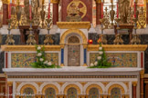 <center>Le maître-autel.</center>Le tabernacle en vermeil est encadré de deux colonnes et de deux panneaux de mosaïque représentant des colombes buvant dans un calice. Sur la porte du tabernacle, l'agneau aux sept sceaux. Photo 2025.