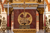 <center>Le maître-autel.</center>En bas du crucifix, deux anges portent chacun un écusson. Sur les branches de la croix figurent les attributs des quatre évangélistes : à gauche, le boeuf de Luc, à droite le lion de Marc, en bas l'homme de Matthieu, en haut l'aigle de Jean.