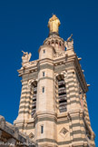 <center>Notre-Dame de la Garde</center>Vue des terrasses supérieures. Plaqué contre la façade sud du clocher, un escalier octogonal permet d'accéder à la terrasse et de là à l'intérieur du campanile et de la statue.