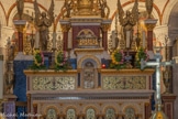<center>Le maître-autel.</center>Le tabernacle en vermeil est encadré de deux colonnes et de deux panneaux de mosaïque représentant des colombes buvant dans un calice. Au-dessus du tabernacle, l'agneau aux sept sceaux, et deux anges de chaque côté de la colonne. Photo 2024.