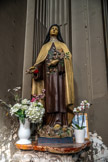 <center>L'église de La Trinité. </center> Chapelle de la Vierge. À l'entrée de cette chapelle se trouvent à gauche une statue de sainte Thérèse de l'Enfant-Jésus, et à droite une statue de sainte Rita de Cascia. Statue de Sainte Thérèse de l'Enfant Jésus revêtue de son habit de carmélite tenant dans ses mains un crucifix et faisant tomber des roses. Plâtre polychrome, probablement entre 1923 et 1925.