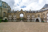 <center>Chantilly. Les grandes écuries. </center> La cour des remises, située à l'arrière du manège découvert, est large de 44 mètres et longue de plus de 46 mètres. Les arcades plein cintre de ses ailes font écho à celles du bâtiment principal, mais aussi aux élévations des écuries de Versailles qui ont des écoinçons à médaillon. Elle est entourée de remises à carrosses et à chaises. Au fond, la cour des chenils.