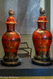 <center>Paire de potiches couvertes sur piédouche.</center>Berlin, XIXe siècle Faïence laquée, bois.
Legs Jules Cantini, 1917. Fonds Musée Cantini.
Marseille, Château Borély - Musée des Arts décoratifs, de la Faïence et de la Mode.
Sur un fond en émail « haricot de Chine », un paysage lacustre se déploie sur la panse, encadré à la base par une frise à fleurs et feuilles de bananier et de treillis à semis de fleurs au niveau de l’encolure. Le motif, esquissé de façon sommaire dans les tons gris et brun, est inspiré des peintures chinoises de paysage. Certains éléments ornementaux paraissent en relief, relevés par une couche supplémentaire de laque. Le couvercle est surmonté d’un coq, dans une teinte imitant le bronze. Le goût pour le laque à forme et décor chinoisant se révèle prégnant au XIXe siècle en Occident.