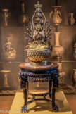 <center>Ekâdaéamukha Avalokitesvara</center>Chine.
Dynastie Ming (1368-1644) ?
Bronze doré. Ekâdaéamukha est une forme interprétative du bodhisattva de la compassion, Avalokitesvara, Guanyin en chinois. Doté de onze têtes et d’une multitude de bras, le Saddharmapunç/arTka Sütra (le Sùtra du Lotus de la Bonne Foi) le désigne comme « [celui] qui fait face partout » (samontamukha). Comme le rappelle Gilles Béguin, « [les] onze faces correspondent chacune à l’une des régions de l’espace de la cosmographie indienne (points cardinaux, points collatéraux, centre, zénith et nadir) ». Une autre version raconte que la divinité, en proie au désespoir, se serait décomposée en dix morceaux. Les dix têtes couronnées sont encore comparées aux dix étapes du chemin spirituel de Bouddha. 
<br>Petite table à encens
Fin dynastie Qing (1644-1911) - République (1912- 1949), fin XIXe - début XXe siècle Bois de Padouk, marbre.