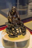 <center>Luohan</center>Chine. Dynastie Qing (1644-19111) Bois de zitan.
Cette pièce représente un des luohan, ou arhat en sanscrit, qui soutiennent le Bouddha Sakhyamuni dans son œuvre de prédications auprès des fidèles. Suivant le canon pali du bouddhisme Teravada, alors que Siddharta Gautama est sorti du Cycle des réincarnations (samsara) en atteignant l’éveil (bodhi), ses disciples ayant atteint comme lui l'élimination choisisse de renoncer au nirvana et de rester sur terre pour répandre son enseignement jusqu'à l'arrivée de Maitreya (Milefo en chinois), le Bouddha du futur. Ce thème iconographique apparaît pour la première fois sous les Tang (617-907) et devient par la suite un véritable poncif dans l’art chinois. 
Don Marie Grobet, 1919. Marseille, Musée Grobet-Labadié