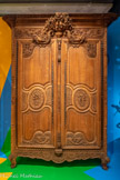 <center>Armoire de mariage</center>Anonyme Calvados, France Vers 1800
Bois de chêne, laiton, fer 
Mucem<br>
En plus de ses décors sculptés, cette armoire a la particularité d'être réalisée selon la technique dite du merrain : pour produire un effet naturel de décor sur les panneaux des portes et des côtés, l'ébéniste a utilisé du chêne dont les planches sont extraites en fendant le bois dans le sens du fil