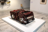<center></center>CÉSAR
(César BALDACCINI, dit)
1921 Marseille (France)
1998, Parti (France)
Renault 977 VL 06
1989
Voiture compressée
Inv. C.98.10.9. Donation do l'artiste, 1998
César est sculpteur, il a développé une œuvre dans laquelle se détachent quatre procédures majeures, tantôt classique (moulage) et tantôt moderne (assemblage), et les siennes propres : compression et expansion. Formé à rÉcole des Beaux-Arts de Marseille puis de Parte, c'est par manque d'argent quH s'intéresse aux matériaux de récupération. En travaillant la ferraille et les rebuts, I leur donne une seconde jeunesse, héritier en cela de l’esprit Dada’.
Vers la fin des années 1950, César découvre rexistence, aux États-Unis, de presses capables de compresser des voitures. L'arrivée dans les usines Renault de la première presse hydraulique en France, lui permet de réaliser des Compressions d’automobiles (i960) qui sont exposées à Parte, créant le scandale. Laissant dans un premier temps la priorité à foutH, dés 196L il intervient sur le matériau, la couleur, la disposition et le degré de compression lui-même, créant les Compressions dirigées. * J'étais les mâchoires qui écrasaient le mêtaL [_] Dans ma tête, c’est moi qui presse, c'est moi la mochine,)efoès corps avec elle.4
Cette appropriation d'un objet industriel, en fera une des figures des Nouveaux Réalistes. Pierre Restany l’invite en 1960 à se joindre aux artistes signataires (Klein, Arman, Raysse, Villeglé. Hains, etc.) de ce qui sera le manifeste du groupe.