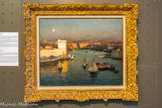 <center>Jean-Baptiste Olive (1848-1936)</center>Entrée du Vieux-Port vue du Pharo. Huile sur toile 50 x 73,5 cm.
Marseillais de naissance, Jean-Baptiste Olive a passé l'essentiel de sa vie à Paris, où il s'installe dès le début des années 1880 et demeure jusqu'à la fin de ses jours. Il n'en est pas moins passé à la postérité comme le peintre par excellence du littoral depuis la Côte Bleue jusqu'à l’île Maïre, et tout spécialement du Vieux-Port inlassablement immortalisé lors de ses retours réguliers en terre provençale.
Poste d'observation privilégié de ce Vieux-Port et des mouvements des navires dans la passe, le promontoire du Pharo a vu passer plus d'un peintre paysagiste, et Olive peut-être plus qu'aucun autre. Son heure de prédilection est la toute fin du jour, lorsque le soleil bientôt disparu embrase le fort Saint-Jean et les immeubles du quai des Belges, comme noyés dans une brume de beau temps qui réduit à une ombre le massif de Saint Cyr, tandis que la pleine lune est déjà bien visible.
L'œuvre n'est pas datée mais deux indices permettent d'esquisser des bornes temporelles. Le haut clocher de l'église des Réformés se dresse déjà à l'extrême-gauche, on est donc après 1886 ; mais le pont transbordeur n'est pas encore construit, ce qui nous ramène avant 1905 - sans certitude toutefois car Olive, qui ne faisait pas partie des enthousiastes de la modernité industrielle, a très bien pu dérider « d'oublier » de le faire figurer...
