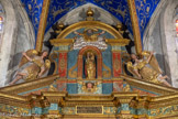 <center>L’église Saint Corneille de Puycelsi</center>Couronnement : fronton encadré par deux statues d'ange en consoles, et avec une statue de Vierge à l'Enfant dans une niche. La Sainte Vierge au rosaire est encadrée par deux anges à demi couchés et placée au-dessus d’un chérubin. Sous la Sainte Vierge, un cartouche en latin: SAINT, SAINT, SI QUELQU’UN N’EST PAS SANCTIFIE, N ‘APPROCHEZ PAS! L’ensemble est dominé par Dieu le Père apparaissant  au-dessus des nuages et bénissant le Monde.