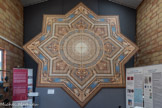 <center>Paray le Monial </center>La FRESQUE de la Société Paul Chamoz & Cie de Paray-Le-Monial, Médaille d’or à l’Exposition Universelle de Paris de 1889.
Origine des motifs décoratifs :
« Le style décoratif de la fin du 19ème siècle, que l’on qualifie « d’éclectique s’inspire des styles historiques et reprend, en les mélangeant, les thèmes les plus significatifs des siècles précédents. Ainsi, cette fresque néo-Renaissance dans son ensemble reproduit des motifs décoratifs du 16ème siècle.
Cependant le registre décoratif général de cette fresque s’inspire non des revêtements de sol de l’époque de la Renaissance, mais plutôt de l’ornementation des plafonds :
La partie centrale rappelle les « ciels » en trompe - l’œil de certains décors.
La forme des motifs entourant les « grotesques » reprend celle des plafonds à « caissons » où les bandeaux semblent imiter des moulures dé bois.
Les motifs de coquilles des angles extérieurs reproduisent des décors de lambris du début du 17ème siècle.
L’originalité de cette fresque est dans le choix des coloris, vifs et variés, le bleu notamment, tonalités que l’on retrouve dans la décoration intérieure d’édifices du début du 17ème siècle (chambre bleue du château de Cormatin, en Saône-et-Loire, par exemple).
Enfin, par des dégradés subtils, les couleurs contribuent à donner l’illusion de relief, à créer un trompe - l’œil, tout à fait en accord avec l’esprit de la Renaissance. » Fresque de 40 m2 réalisée en carreaux de grès dessinés par incrustation composée de 700 carreaux de 17,5cm x 17,5cm.