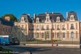 <center>La Préfecture. </center> L'architecte est Guérinot, comme la mairie. Commencé en 1864, le bâtiment est terminé en 1868. Il s'inspire du style Louis XIII, avec des toits à la Mansart, de style Louis XIV. La partie centrale est accosté de deux grandes ailes en retour. Les combles sont percées de fenêtres et d'oculi. La façade est en briques recouvertes de stuc peint en rouge imitant des briques.