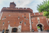 <center>Le Castillet.</center>À partir du dernier tiers du 14e siècle, on entrait dans Perpignan, après avoir franchi un pont plusieurs fois reconstruit, le pont à dos d'âne, par une porte fortifiée, le Castillet. Il fut édifié au milieu du rempart pour surveiller le passage du pont de pierre et les entrées dans la ville. Agrandi par la porte Notre-Dame sous Louis XI, en 1483, il devint une forteresse autonome enserrée au 16e siècle dans le bastion de Charles-Quint. Construit en briques, avec ses ouvertures appareillées de pierre de taille, transformé en prison du 16e au 19e siècle, puis en musée au 20e, il est devenu l'emblème de la ville.