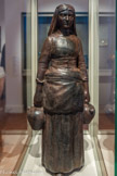<center></center>Musée Hyacinthe Rigaud. <br> Gustave Violet
(Thuir, 1873 — Perpignan, 1952)
Catalane aux cruches, 1911
Terre cuite patinée
Violet aime à représenter les petites gens de son pays.
Ici, une catalane, la jupe simplement ramenée sur les hanches, revient de la fontaine. L'immobilité solide l de ce corps raidi par la pesanteur des deux cruches emplies d'eau, le visage impassible encadré par le foulard qui tombe sur la nuque incarnent le difficile chemin emprunté par Violet: chercher dans ses racines et sa province des figures universelles.