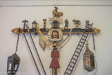 <center>Ancien évêché</center>Immédiatement après le regidor rouge, s’avance, encadrée par deux caparutxes noirs, la Croix des Outrages ( Creu dels Improperis). Cette croix de procession de bois polychrome représente sous la forme traditionnelle populaire et imagée, les seize groupes d’objets symbolisant les souffrances infligées au Christ et détaillées dans les Évangiles, depuis la trahison de la Cène jusqu’au coup de lance du légionnaire. Ce type de croix est souvent exposé dans les chapelles consacrées à la Passion.