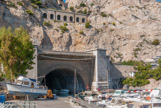 <center>L'Estaque.</center>Entrée sud du tunnel du Rove. Il mesure un peu plus de 7 km et relie l'étang de Berre au port de Marseille, à l'Estaque. Ce n’est qu’au début du XIXe siècle qu’on imagine pour la première fois de passer sous la chaîne de l’Estaque pour rejoindre rapidement les eaux calmes de l’étang de Berre, propices à la navigation des navires de charge. Un avant-projet, présente en 1841 par Montricher, propose la réalisation d’un tunnel de 5 040 mètres de long qui franchirait les collines de la Nerthe à une altitude de 50 mètres… imposant la construction de quarante-huit écluses. Le Blanc propose en 1873 la solution qui sera finalement retenue : le tunnel navigable sera maintenu au niveau de la mer, ce qui évite la construction d’écluses. l faudra cependant encore attendre trente ans pour que le projet soit réellement lancé. La jonction entre les galeries nord et sud a lieu le 16 février 1916. Plus de dix ans plus tard, le 3 août 1926, et après quinze ans de travaux, le chantier du tunnel du Rove est enfin achevé. La première traversée a eu lieu le 23 octobre 1926, elle prend en moyenne 2 heures. Mais, dans la nuit du 16 au 17 juin 1963, le tunnel du Rove s’effondre sur 200 mètres de longueur. Le tunnel est depuis lors fermé à tout trafic.