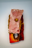 Sans titre (Croûûûtes), 2018. Polystyrène extrudé Collection Philippe Gellman
Cette œuvre fait partie de la série des « Croûûûtes », dont le titre évoque non seulement la croûte terrestre ou une mauvaise peinture mais également le son que fait le médium quand on le touche ou quand il craque ou brûle (crrrrr). Son aspect quant à lui rappelle plutôt un corps écorché ou calciné. Toutes les plaques polypropylène de la série proviennent d’une entreprise dirigée par une femme trans, amie de l’artiste. Le matériau est travaillé au chalumeau puis au décapeur thermique pour unifier les parties. « Il y a peut- être de l'acétone en plus. Je balance l’acétone et puis je rince. Il y a plusieurs outils de fonte pour créer différentes formes [...]. Ce sont des morceaux de terre brûlée ».
Les « croûûûtes » apparaissent dans le travail d’Anita Molinero dès 2002 sous la forme de murs, de plafonds, de sols ou d'énormes sculptures en forme de blocs. Ce n’est que plus tard qu’elles s’autonomisent de leur environnement pour devenir tableau. Certaines sont encadrées avec du Plexiglass® coloré, d’autres aspergées de couleurs appliquées trop rapidement. L’artiste s’amuse et se moque avec joie de la peinture et ses dogmes.