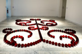 James Lee BYARS
1932, Detroit (États-Unis) 1997, Le Caire (Égypte)
Le petit ange rouge
1991-1993
Verre massif travaillé à chaud.
Inv. 1993.8.1
Production / réalisation Cirva Collection Cirva. Marseille.
Après des études de philosophie et d'art dans sa ville natale James Lee Byars découvre le Japon, qui sera pour lui une source d'inspiration capitale. Il y développe l'idée qu'un concept seul peut être un objet esthétique, ce qui deviendra un thème pour le reste de sa carrière. Son travail de performances, installations et sculptures, empreint de spiritualité prend source dans différentes cultures, mythologies et philosophies, à la fois orientales et occidentales, archaïques et tribales. Il est hanté par l'éphémère et la mort
Ainsi The Rose Table of Perfect (1989), où les 3333 roses rouges qui composent la sculpture se fanent tout au long de l'exposition. Et The Perfect Death of James Lee Byars (1984) dans laquelle l'artiste est vêtu d’un costume en lamé or et étendu sur le sol peint en or. Son corps, ton sur ton, se fond dans la couleur.
Le Petit Ange rouge est composé de 333 sphères de verre soufflées et moulées à la main dans l'atelier du Cirva à Marseille. Les boules décrivent des volutes symétriques évoquant l'art des jardins à la française, un arbre de vie. Rouge sang, posées au soi comme un collier formant des arabesques, les boules de verre en dessinent les contours, ou le spectre. La couleur vibrante de l'œuvre évoque la chaleur de la vie mais aussi la profondeur de la mort qui, dans les sociétés asiatiques, est souvent associée à l'idée d'une renaissance.