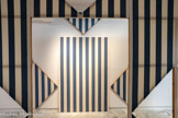 Daniel BUREN
1938, Boulogne-Billancourt (France)
Cabane éclatée n° 2
1982
Bois, toile de coton à rayures verticales bleues et blanches, éléments projetés, serre-joints, acrylique blanche
inv.c.92.6 Achat 1992.À propos de la Cabane éclatée n°2, il explique : « Soit la construction d'une boîte de 420 cm de long par 280 cm de large en panneaux de 140 cm de large chacun par 280 cm de haut Chacun de ces châssis est tendu de tissu, ici blanc et bleu. Des dessins particuliers sont effectués dans ces châssis, permettant d'en ôter des fragments qui constitueront des 