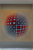 <center>L’ALVEOLE 6</center>VEGA ANNAUX -1969
582 x 582 
Tapisserie réalisée à Aubusson. Suspendue directement au mur par jeu de bandes Velcro cousues sur l’œuvre et collées au mur. Fond gris foncé.
L’illusion d’optique de l’immense sphère est le résultat des recherches de l’artiste sur la déformation de la ligne qu’Il mixe aux éléments de son alphabet plastique. L’effet de volume expansé des formes est renforcé par les couleurs en dégradé qui semble faire émerger la sphère d’un halo d’opacité.