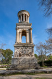 <center>Le mausolée des Julii.</center>La partie basse ne renferme pas de chambre funéraire, le monument est donc un cénotaphe et non un mausolée. Les faces de la base carrée sont sculptées de scènes historiques et mythiques. Ici, face Ouest : une scène de bataille de la guerre de Troie avec des fantassins et le combat pour récupérer le corps de Patrocle.