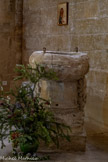 <center>L'église Saint-Trophime-Saint-André</center>Au cœur de cette « chapelle du Seigneur », les fonts baptismaux présentent un chapiteau de colonne inversé où l'on peut voir un animal sculpté, un loup rampant et campé sur ses pattes. Ce blason de la famille d'Agoult-Montauban fait partie des armoiries de Lourmarin. Ces fonts sont constitués d'éléments en remploi qui pourraient avoir appartenu à un monument funéraire.