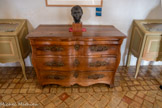 <center>Château de Lourmarin</center>Salle de musique. Trois vitrines présentent une collection de verrerie funéraire romaine, du 2éme-3ème siècle après J. C. . de part et d'autre de la commode « Arbalète ». La commode Arbalète est une commode provençale de style Louis XV qui possède une façade galbée en forme d'arbalète, elle s'ouvre par 2 ou 3 tiroirs.